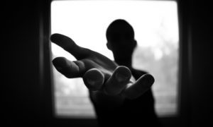 a shadow figure of a man extending his hand asking for help