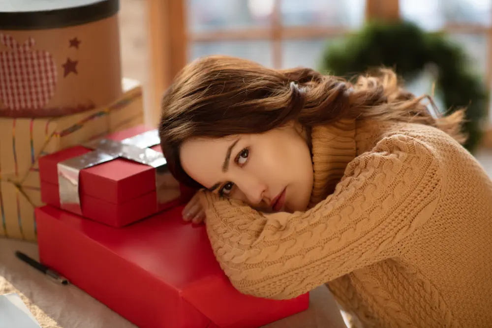 Woman sadly rests her hand on Christmas presents