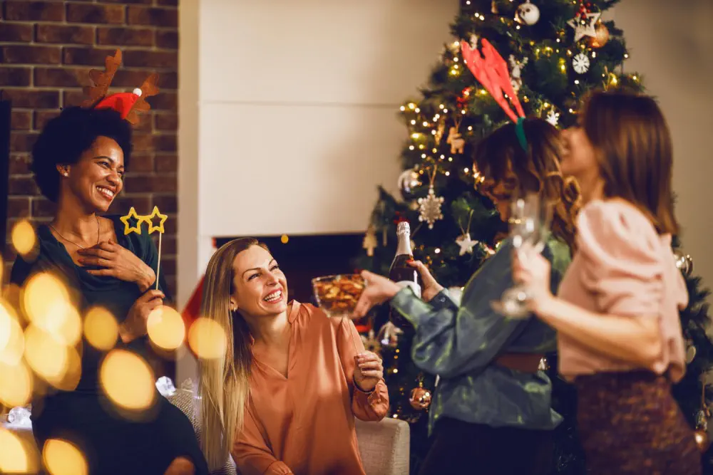 Women celebrating the holidays near a Christmas tree.